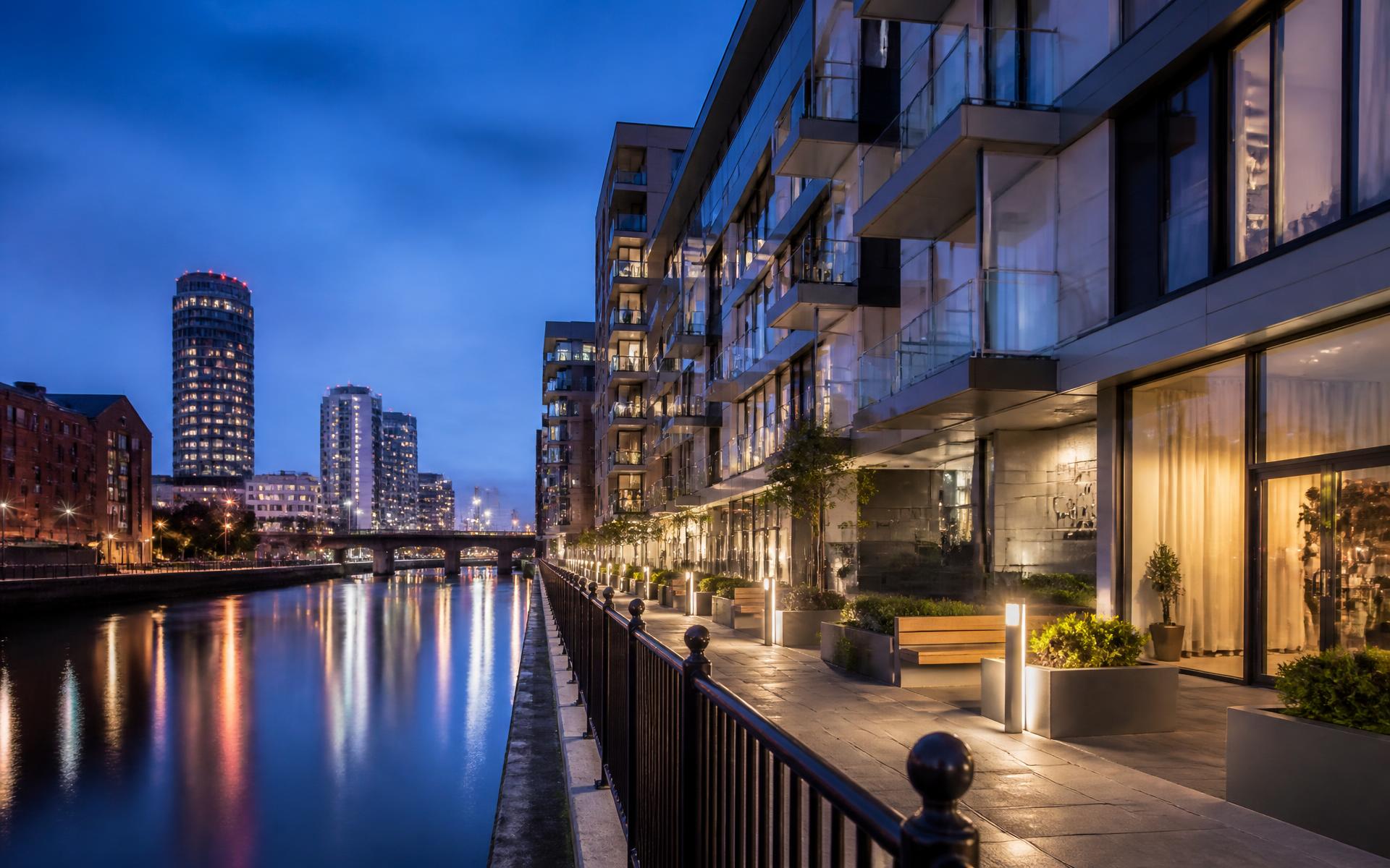 Modern riverside apartment building with glass balconies in Manchester at dusk